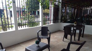 A patio area with a table and chairs, a small potted plant, and a view through a metal fence. - Hermoso y cómodo apartamento en Leticia No 1 (Leticia)