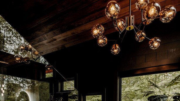 A spa room with a large window, a stone-tiled floor, a wooden ceiling, and a chandelier.