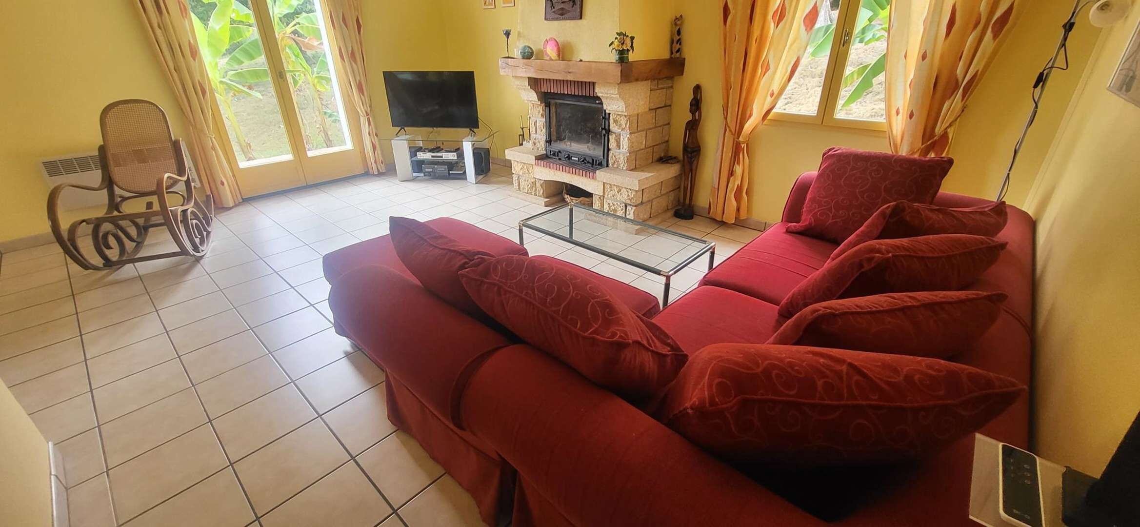 Una sala de estar con un sofá rojo, un televisor, una chimenea y una silla de ruedas.