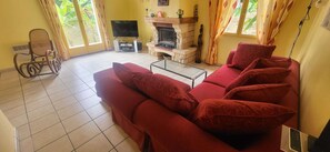 Una sala de estar con un sofá rojo, un televisor, una chimenea y una silla de ruedas.