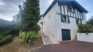 Una casa de dos pisos con una escalera de piedra que lleva a la entrada.