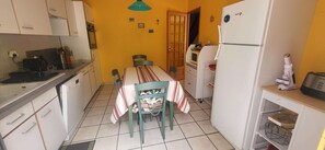 Eine kleine Küche mit Esstisch, Stühlen, Kühlschrank und Mikrowelle.