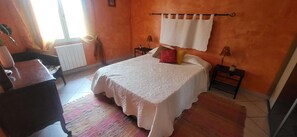 A bedroom with a bed, a chair, a nightstand, a lamp, and a window with curtains. - Quartier du Lac, Saint-Pée/Nivelle, villa 8 couchages (ST PEE SUR NIVELLE)