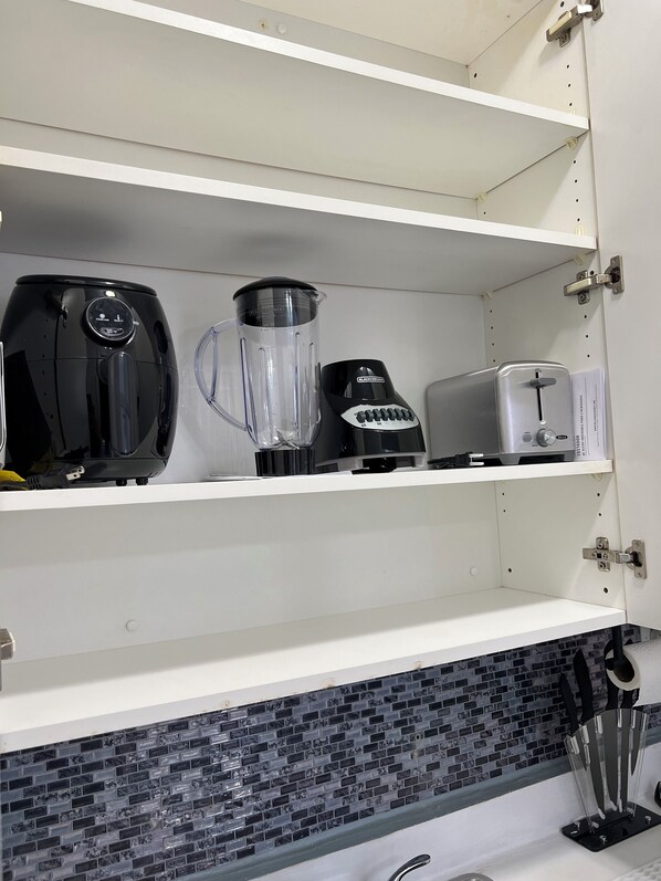 A kitchen with white cabinets, a blender, a toaster, and a coffee maker on the countertop.