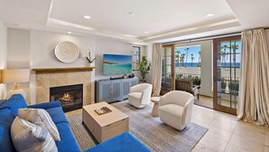 A modern living room with a fireplace, a sofa, a coffee table, and a view of the beach through large sliding doors. - Walk to Beach Lux Oceanview Retreat with Bikes (San Clemente)