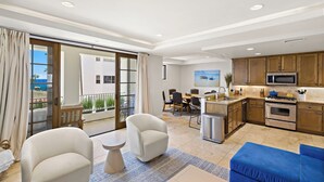 A modern kitchen with wooden cabinets, a microwave, and a stove. There is a dining area with a table and chairs, and a living area with sofas and a coffee table. - Walk to Beach Lux Oceanview Retreat with Bikes (San Clemente)
