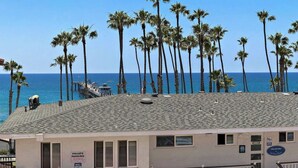 A building with a private parking sign, a view of the ocean, and several palm trees. - Walk to Beach Lux Oceanview Retreat with Bikes (San Clemente)