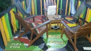 A wooden deck with two hammocks, a table, and chairs.