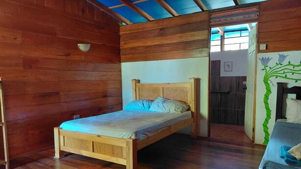 A wooden room with a bed, a small table, and a wall with a decorative design.