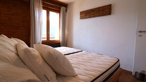 A bedroom with a bed, wooden walls, a window with curtains, and a wooden headboard.