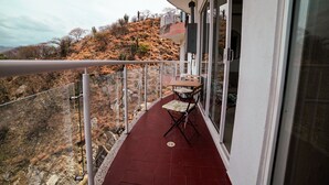 En balkon med rødt gulv, et bord og to stole.