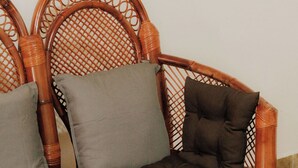 A wicker sofa with cushions and a wooden bench.