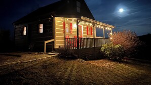A wooden house with a porch, a small deck, and a visible window.