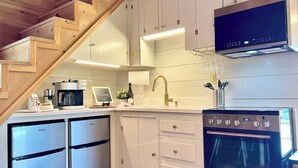 A modern kitchen with white cabinets, a built-in oven, a coffee maker, and a wine glass holder.