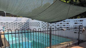 Una piscina con recinzione in metallo nero, circondata da un muretto decorativo bianco con motivi geometrici.