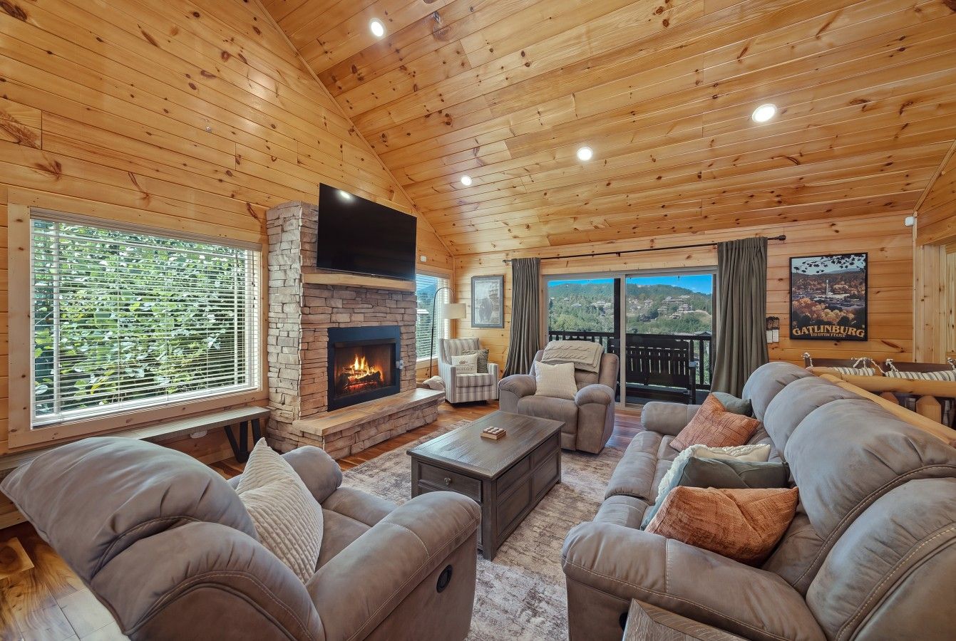 A cozy living room with a fireplace, comfortable seating, and large windows offering a view.