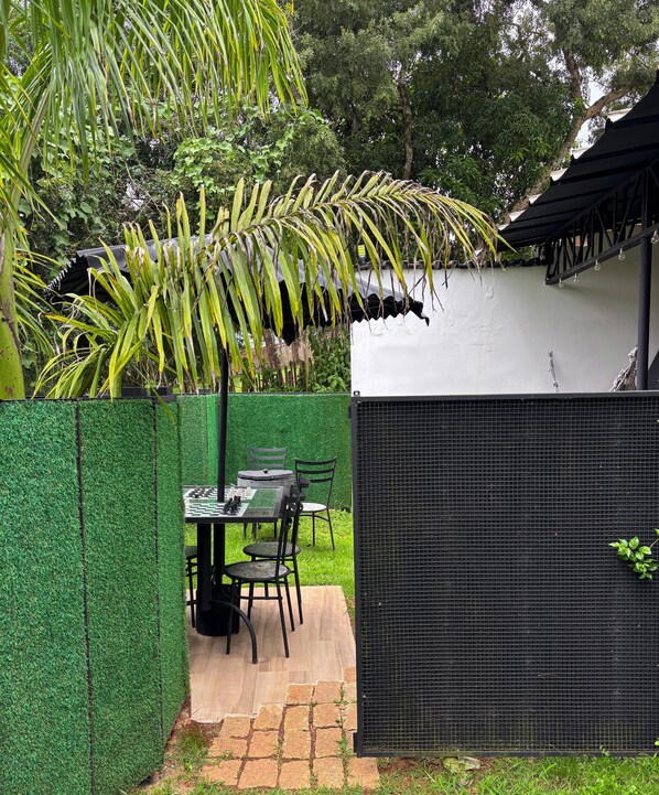 Une terrasse avec une table et des chaises, un mur végétal et une clôture en treillis noir.