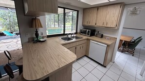 A modern kitchen with wooden cabinets, a microwave, a toaster, and a sink. - Furnished house in Dunedin. Canal view. Close to Downtown, Beaches & Stadiums  (Dunedin)