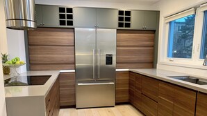 Una cocina moderna con refrigerador de acero inoxidable, armarios de madera y ventana con vistas al exterior.
