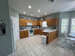A kitchen with wooden cabinets, a white stove, and a window with blinds.
