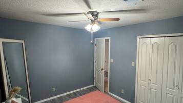 Une chambre à coucher avec un lit, un ventilateur de plafond, une porte et un placard.