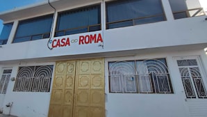 Ein zweistöckiges Gebäude mit einem Schild, auf dem "CASA ROMA" steht, über einer großen, goldenen Tür.