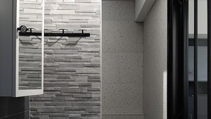 A modern bathroom with a stone wall backsplash, a white sink, and a shower area. - IDEAL FOR YOUR SPA TREATMENT IN SANTENAY (Chagny)