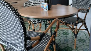 A dining area with a round table, black and white checkered chairs, a vase with flowers, and a black-framed door. - IDEAL FOR YOUR SPA TREATMENT IN SANTENAY (Chagny)