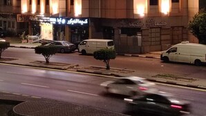 A multi-story hotel with illuminated signage in Arabic, a parking area, and a street with vehicles. - asyl hotel (Taif)