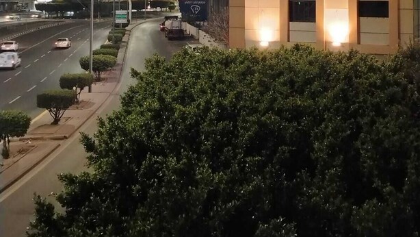 A modern building with illuminated signage, a well-lit entrance, and a road with vehicles in the background. - asyl hotel (Taif)