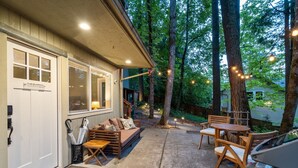 A covered patio with a sofa and chairs, string lights, and a car parked nearby. - Private Urban Forest Hideaway in the Heart of Portland with AC (Portland)