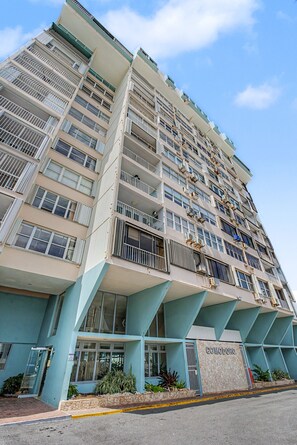 A multi-story hotel with balconies, a stone facade, and a sign reading 'COMODO'. - Caribe Aqua Loft  Steps to the Beach  3BR Condo (Isla Verde)
