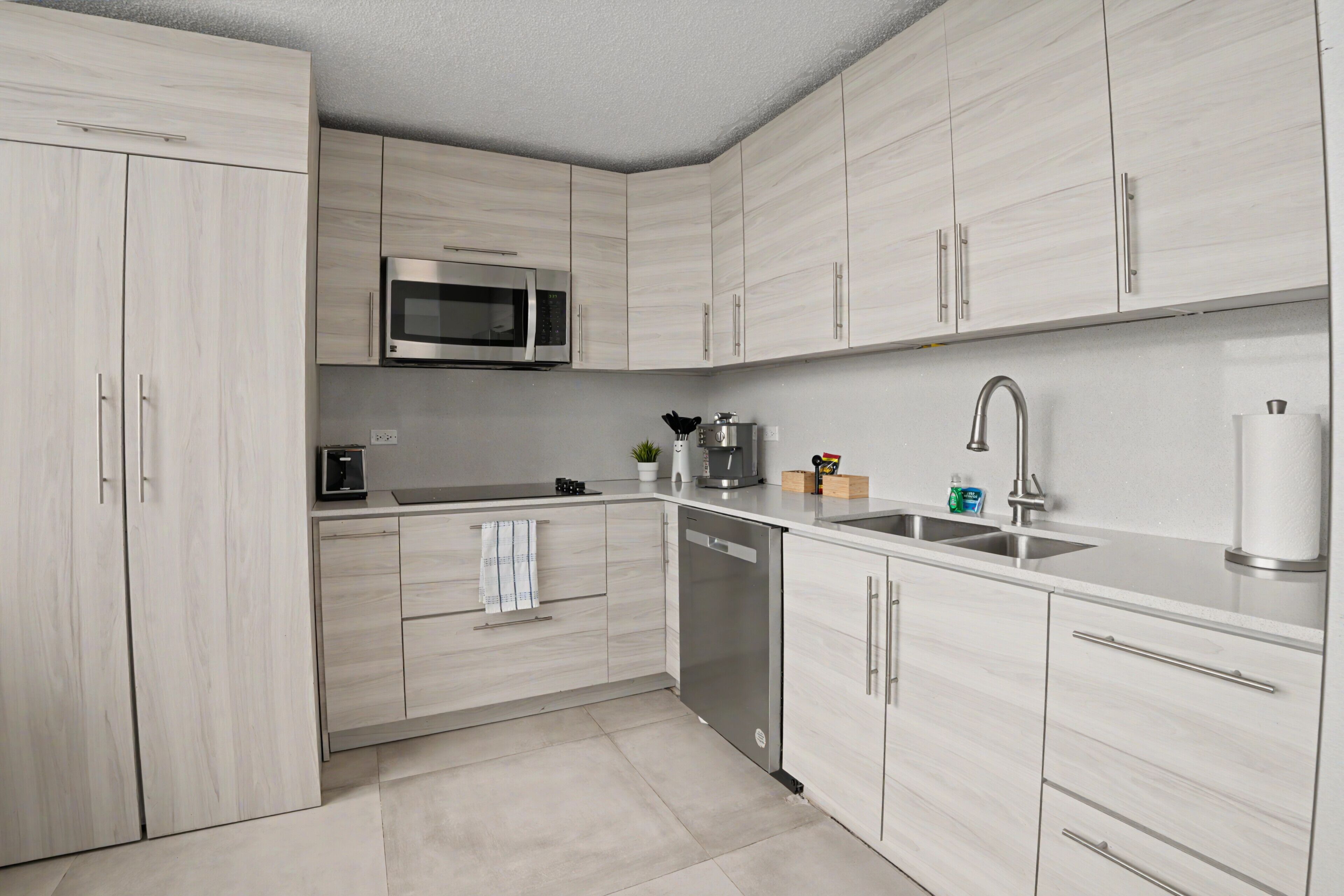 A modern kitchen with light wood cabinets, stainless steel appliances, and a clean layout.