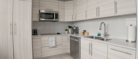A modern kitchen with light wood cabinets, stainless steel appliances, and a clean layout.