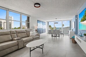 A modern living room with a sofa, a coffee table, and a dining area with chairs and a table. - Caribe Aqua Loft  Steps to the Beach  3BR Condo (Isla Verde)