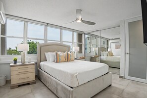 A bedroom with a large bed, a nightstand, a mirror, and a ceiling fan. - Caribe Aqua Loft  Steps to the Beach  3BR Condo (Isla Verde)