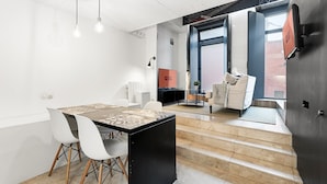 Un espace repas moderne avec une table, des chaises et, au fond, un coin cuisine.