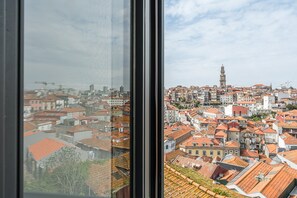 Eine Stadtansicht mit einem markanten Turm, dichter Bebauung und Blick durch ein Fenster.