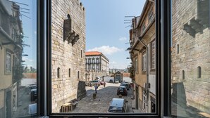 Une rue étroite bordée d’immeubles en pierre, avec un chemin pavé et des voitures garées.