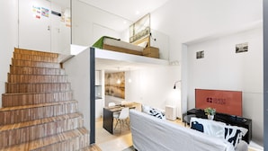 Un intérieur moderne comprenant un escalier, un lit superposé, un coin repas et un téléviseur.