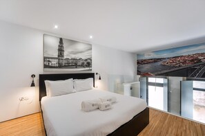 Ein modernes Hotelzimmer mit einem großen Bett, einem Stadtbild-Wandgemälde und Blick auf eine Brücke.