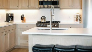 Una cucina moderna con mobili in legno, elettrodomestici in acciaio inossidabile, un'isola centrale con sgabelli e una lampada a sospensione.