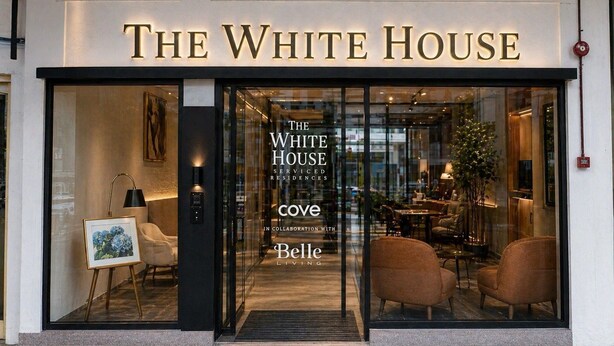 Entrada de un hotel con un letrero que dice 'The White House' y una puerta de vidrio.