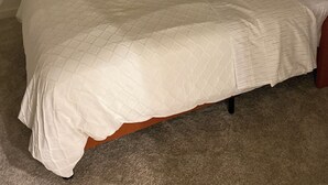 Una camera da letto con un letto, un comodino, una lampada e un condizionatore d'aria a parete.