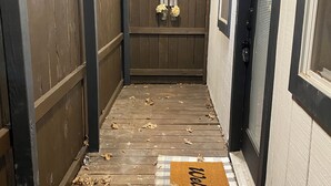 Un pontile in legno con un tappetino d'ingresso e foglie sparse.
