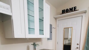 Une cuisine avec des meubles blancs, un plan de travail en granit et un plancher en bois.
