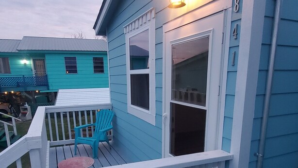 Une maison bleue avec un porche blanc, une lanterne et le chiffre « 8 » sur le côté.