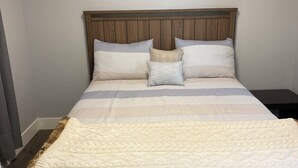 A neatly made bed with a wooden headboard, multiple pillows, and a white quilt.