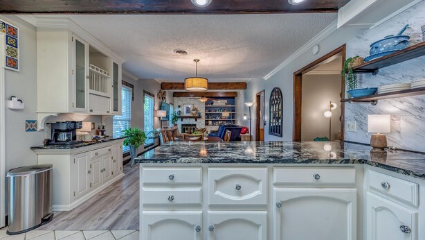 A spacious kitchen with white cabinetry, a marble countertop, and a central island. - Casa Feathergrass (Roswell)