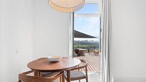 A dining area with a wooden table and chairs, a bowl on the table, and a view of a deck with outdoor furniture. - Guestready - D. Hugo Boutique Hotel B&B (Porto)